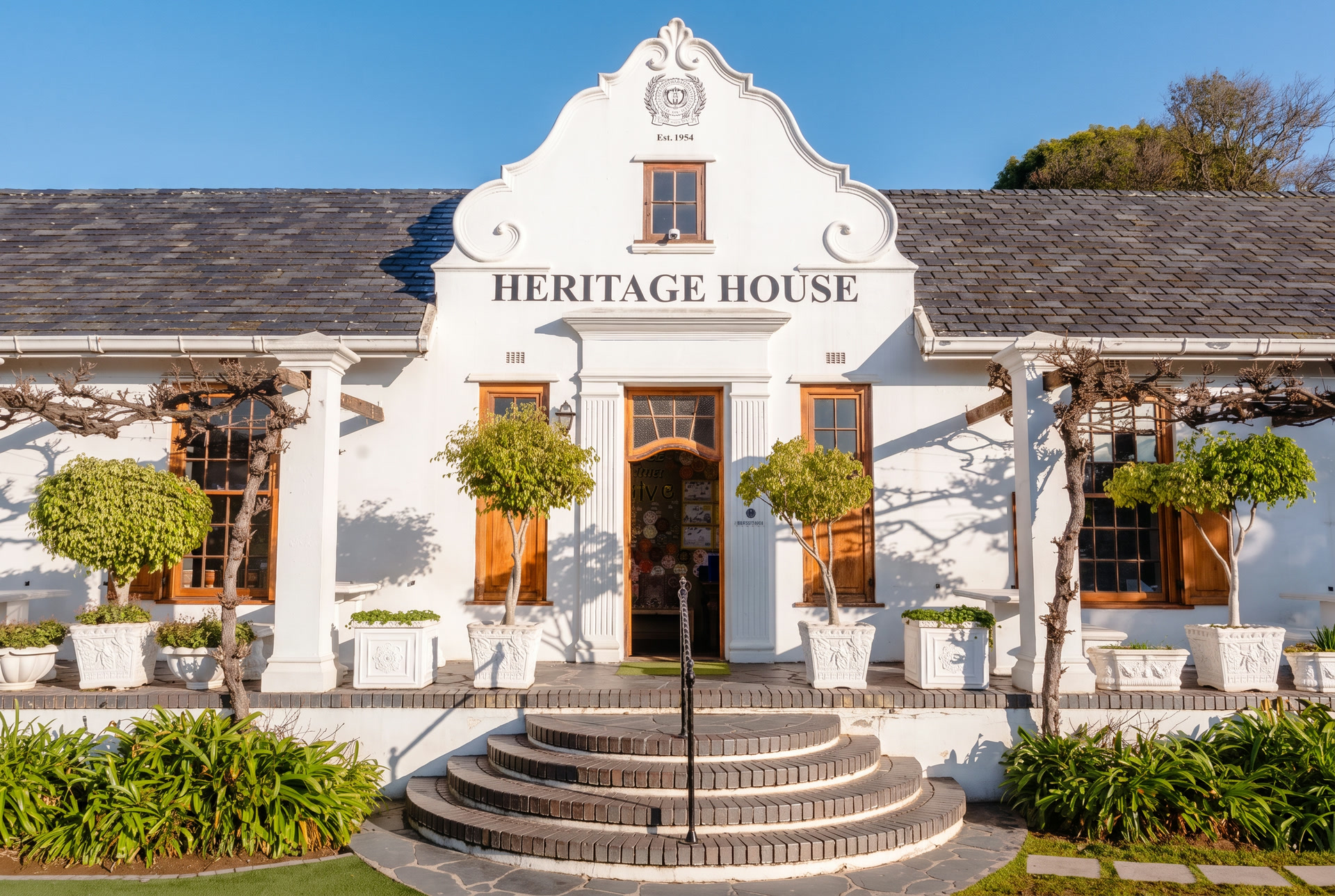 Heritage House Primary School building framed by oak trees with the Paarl mountains behind